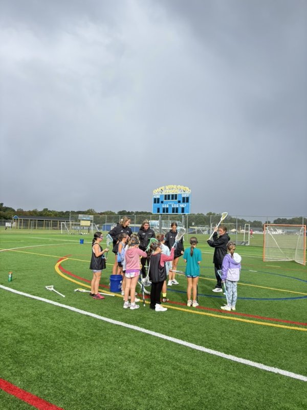 A group of players gets shooting instruction from Cape alumna Ella Rishko, right.